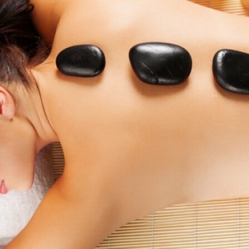 Hot stone massage på kvindes ryg som del af wellnessbehandling i Odense